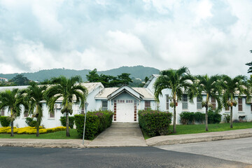 Obraz premium White, one floor white building with palm trees at front and mountains in the background