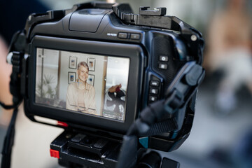 Portrait of a woman giving an interview in the moratorium of a larger video camera. News,...