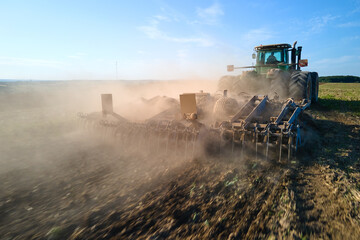 Aerial view of tractor plowing agriculural farm field preparing soil for seeding in summer