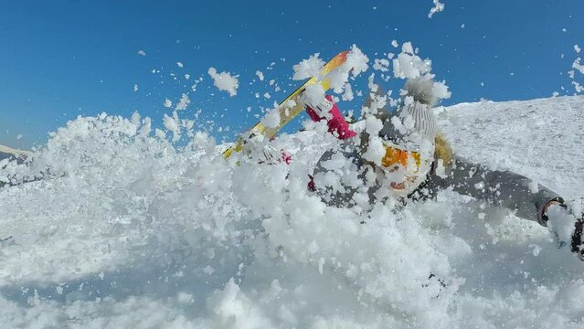 CLOSE UP: Lady trying to make a turn with snowboard when she crashes into snow. Female beginner snowboarder falls towards camera while she is learning to ride a snowboard on slope at snowy ski resort.