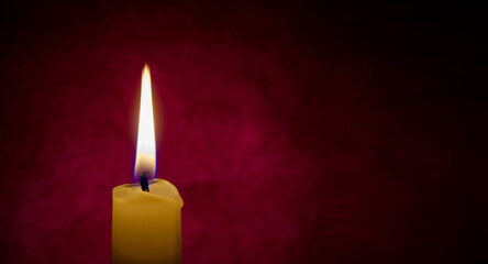 Red candle burning in the dark red background