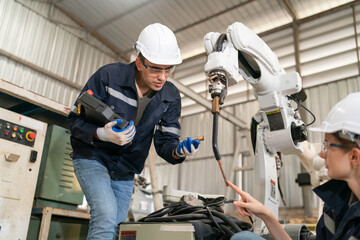 Robotics engineer working on maintenance of modern robotic arm in factory warehouse