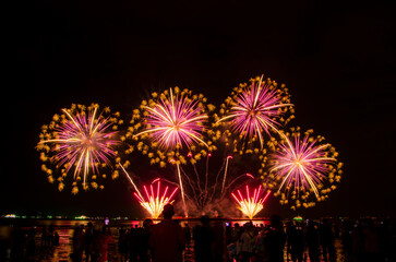 PATTAYA, CHONBURI, THAILAND, NOVEMBER Beautiful lights at the night colorful fireworks, at Pattaya International Fireworks Festival and silhouette Group of people tourist sit and watch