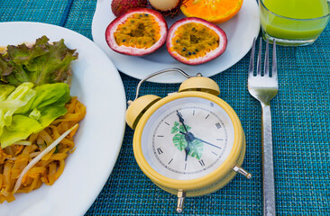 Yellow alarm clock Intermittent fasting eight hour feeding window concept  which diet eating a healthy food background