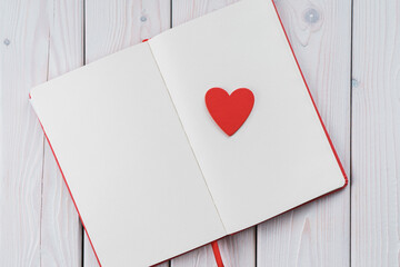 Red diary notebook with white papers, craft red paper heart on page. Love letter message for...