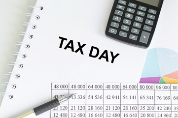 TAX DAY. text on white notepad paper on wood background