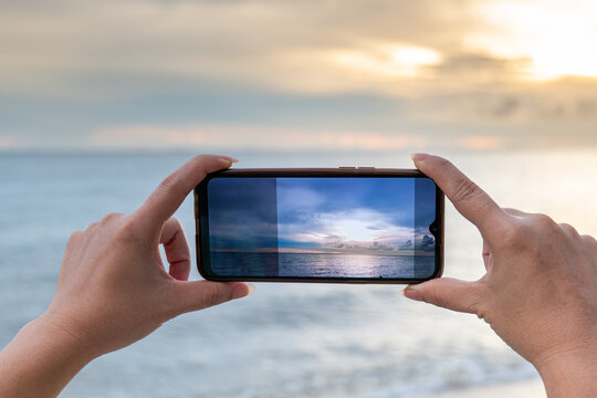 Taking photos on the mobile phone of sea view, taking Photo Vacation time to the Sea, Hand on Mobile take Sea scape view, Mobile take photos of the sea. Soft focus view photo on the display Mobile 
