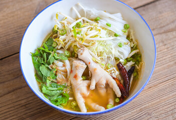 Rice noodles with chicken feet on soup bowl on wooden table food background - Thai food thai rice noodles spicy soup curry with fresh vegetable