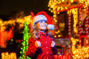 Christmas decoration in front of a night house. Child near night christmas decoration in front of a house. Christmas Evening in the background of the night house with garlands.