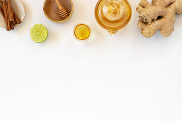 Fototapeta na wymiar Top view of a cup of tea with ginger root, lime, cinnamon and teapot on white background. Health drink concept..