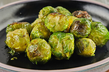 French recipe Brussels sprouts on black plate on wooden background