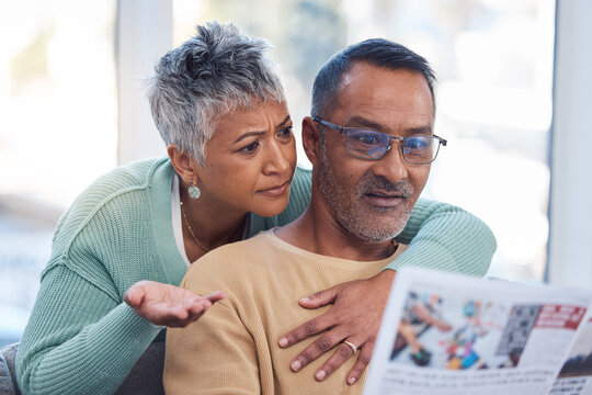 Couple, Shocked Or Confused In Book Reading, Magazine Or Travel Newsletter In Vacation Planning, Holiday Ideas Or Break Location. Mature Woman, Indian Man And Hug With Article Or Print Media In House