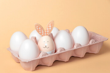 Fototapeta premium The Easter bunny is sitting in a box with white eggs. The concept of approaching the holiday.Festive composition.
