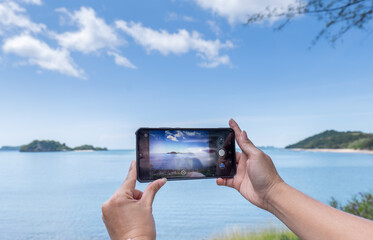 Taking photos on the mobile phone, Take Photos of the seascape view, taking Photo Vacation time to the Seascape, Hand on Mobile take Sea scape view.  