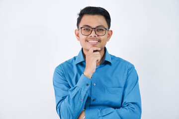 smiling employee asian man with glasses while holding the chin looking camera wearing blue shirt isolated on white background