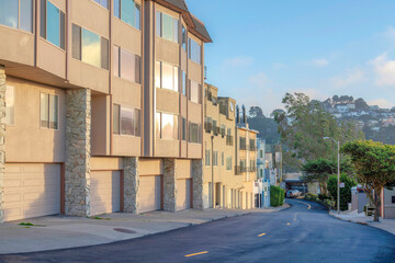Roadside apartment buildings with attached garage and a view of mountain at the back