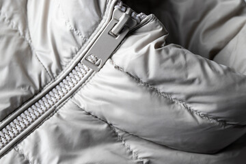 Close up of padded jacket with zipper in grey color. Winter texture