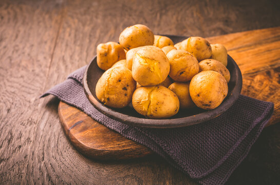 Boiled young potatoes in bowl on cutting board