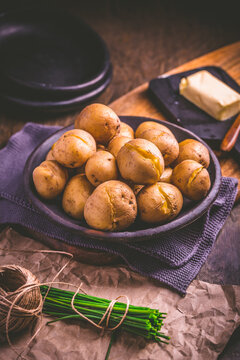 Boiled young potatoes with butter and chives on cutting board