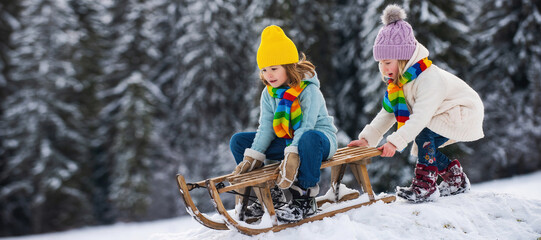 Cute girl and boy enjoying a sleigh ride. Children sledding in snow on winter park.