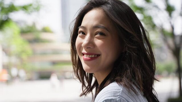 Side view of Charming young asian woman looking at camera smile in the urban sunny day portrait of lovely young people