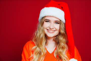 a beautiful woman in a Santa Claus hat on a red background. 