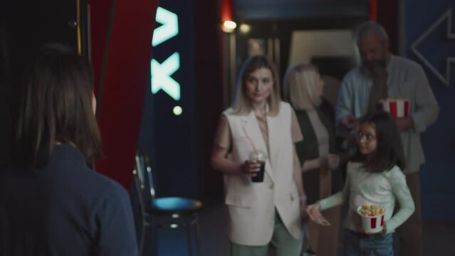 Group of people in queue passing their tickets for movie to cinema hall worker