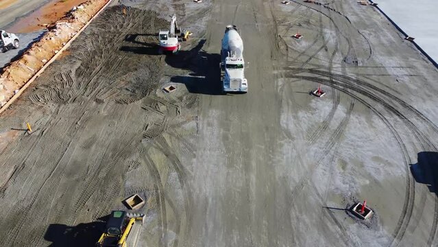 A concrete truck drives toward a concrete pouring site.