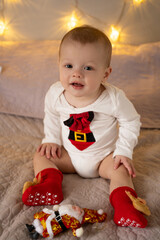 The boy sits and smiles on the sofa in the festive room before Christmas