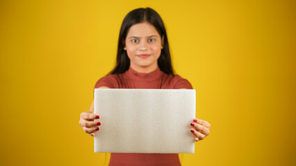 Beautiful young woman holding empty blank white board, your text here concept, Asian Indian girl isolated over colour background studio