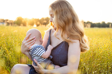 Mom breastfeeds her baby at sunset
