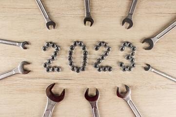 Light wood background with number 2023 by metal nuts with wrenches. 2023 year