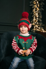 Little child under Christmas tree. baby boy in Santa Claus hat with gifts under Christmas tree with many gift boxes presents. Happy Holidays, New year. Cozy warm winter evening at home. Xmas time