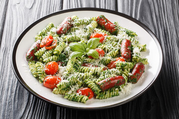 Green Pesto Sausage Pasta with Tomatoes and parmesan closeup on the plate on the table. Horizontal
