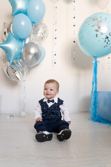 a boy in a festive costume celebrates his 1st birthday, blue and silver balloons, the room is decorated