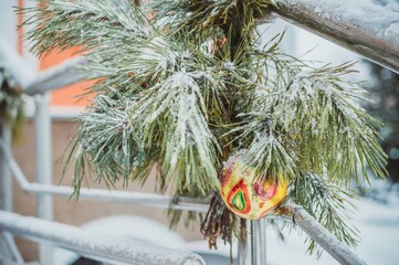 Christmas tree toy on pine branch covered with frost on metal railing