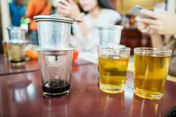Vietnamese coffee in glass cups, traditional metal coffee maker phin. Black drip coffee as famous in Vietnam