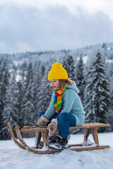 Boy kid enjoying a sleigh ride on winter landscape. Child on sleigh. Child plays outside in the...