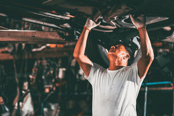 Fototapeta na wymiar Garage worker Asian male mechanic team working car auto service fix replace under car lift hoist