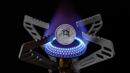 Gas burner with blue flame and bitcoin closeup on dark background.