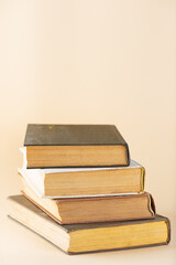 Stack of old books on beige background, education, learning, study. Vertical orientation.