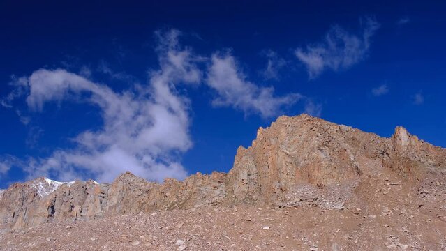 Bizarrely shaped clouds float over rocky mountain peaks