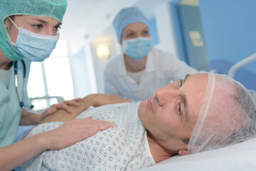 Obraz premium nurse and surgeon assisting patient on bed