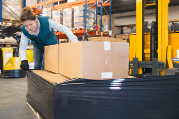 female worker checking shrink wrap on forklift load