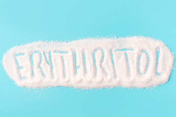 Inscription erythritol on a sweetener close-up on a blue background top view.