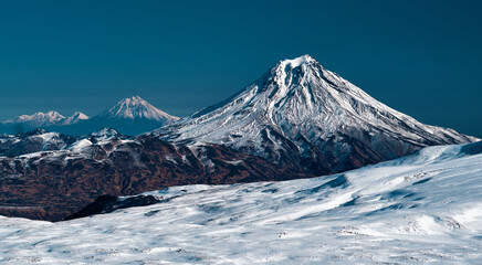 3 mountain peaks of snow in nature panorama..Kamchatka mountains in sunny day. Nature colors.