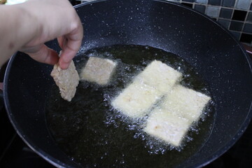 Woman frying tempeh a traditional Indonesian food made from fermented soybeans