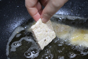 Woman frying tempeh a traditional Indonesian food made from fermented soybeans