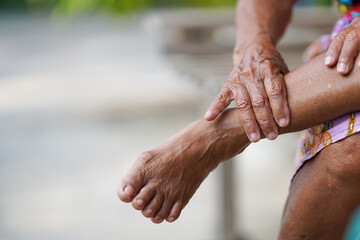 Hand of an elderly woman massaging an ankle with an injury due to arthritis, osteoporosis, tendon...