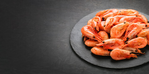 Boiled shrimp on a black slate round board on a black background. Perfect retouching. Copy space. Top and side view. Photos for menus, advertisements.